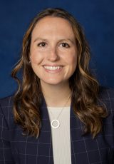 Becky McCain poses in front of a blue background.