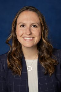 Becky McCain poses in front of a blue background. 