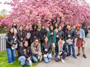 A group of Break Through Tech fellows pose for a photo in front of a flowering cherry blossom tree at the New York Botanical Garden.