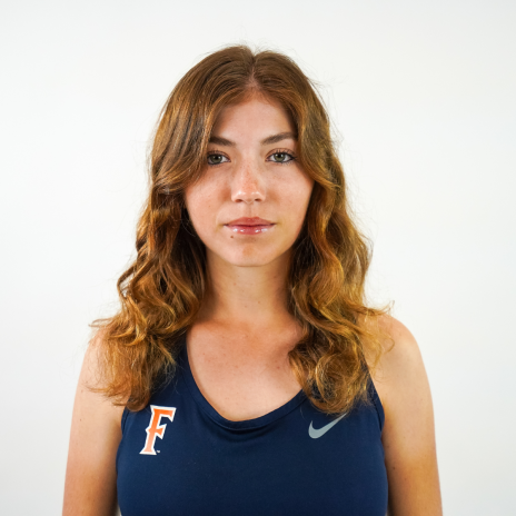 A woman with brown curly hair wears a California State Fullerton sports uniform.